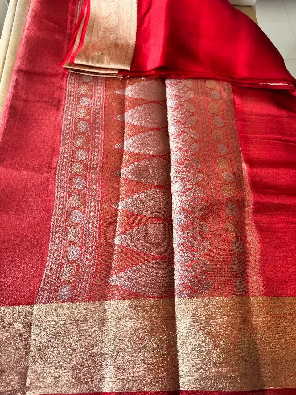 Red brocade tissue pallu spread flat, rows of paisley and flowers in gold